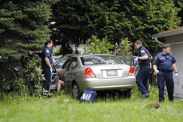 Emergency workers attend to a 78-year-old Finn Hill man who drove his car through garbage cans and also hit a tree