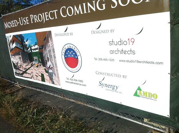 A large banner on Lake Washington Boulevard announces a new mixed-use project is coming soon.