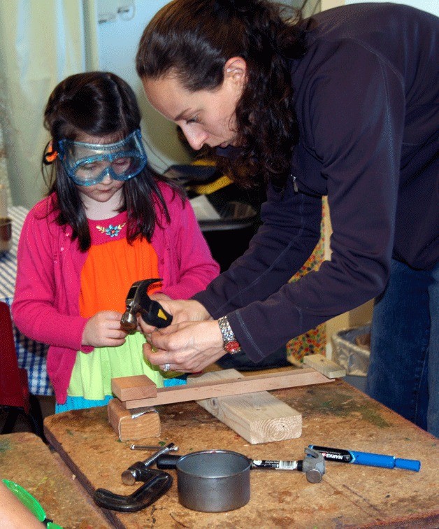 Kirkland Preschool student Isobel learns how to hammer a nail with the help of a teacher on Tuesday afternoon. Two families at the preschool acquired the site more than 10 years ago