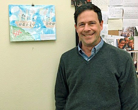 Sen. Andy Hill stands in his Olympia office with art made form a student in his district.