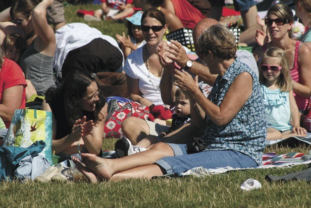 A family claps along to the music at the first children's Kirkland Summer Concert of 2013 at Juanita Beach Park.