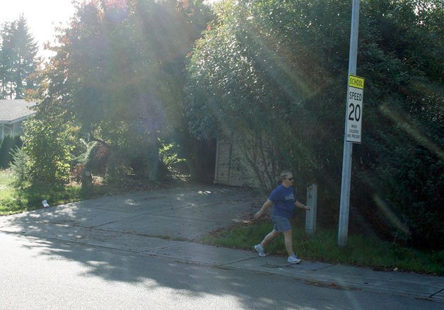 This house in the Juanita neighborhood was the epicenter for a SWAT raid on Oct. 4. The house can be seen here shrouded in the trees and bushes while a neighbor walks along the sidewalk by a school zone sign. The home is 300 feet away from Helen Keller Elementary.