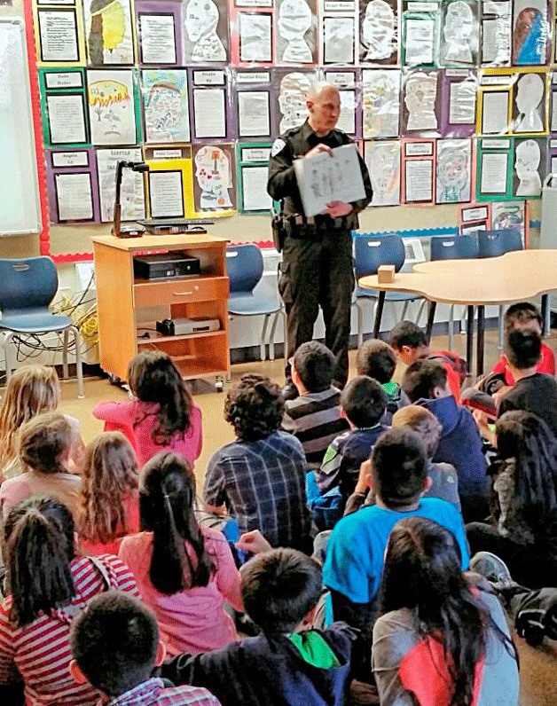 A Kirkland Police Officer reads to students at Muir Elementary.