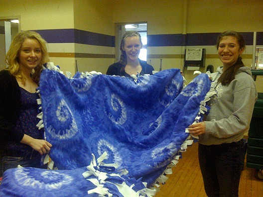 Lake Washington High School students show off a fleece blanket they made for Evergreen Hospice.