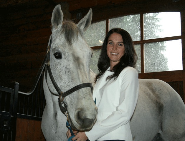 Kelsey Devoille stands in the barn at her Bridle Trails business with one of her therapy horses